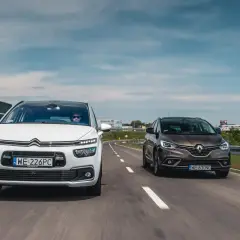 Biały Citroën C4 Grand Picasso i brązowy Renault Scenic jadą obok siebie drogą.