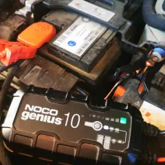 Ładowanie akumulatora na mrozie. Urządzenie NOCO Genius 10 podłączone do akumulatora samochodowego, by zapewnić mu energię w zimne dni.