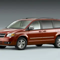 Pomarańczowy Dodge Grand Caravan stoi na szarym tle.
