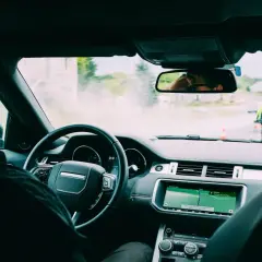 Widok z kabiny samochodu, kierowca uczy się jak jeździć samochodem, nawigacja pokazuje trasę, a przed nim jedzie motocyklista.