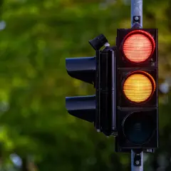 Sygnalizacja świetlna z czerwonym i żółtym światłem. Kierowca zastanawia się, czy zdąży na przejazd na żółtym świetle, czy lepiej zahamować.