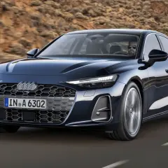 Ciemnoniebieskie Audi A6 C9 z nowoczesnym grillem i światłami LED jedzie po pustynnej drodze.