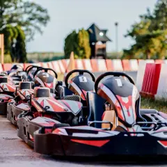 Rząd gokartów z numerami 3, 8 i 1 czeka na torze. Zastanawiasz się, ile kosztują gokarty na taką zabawę?