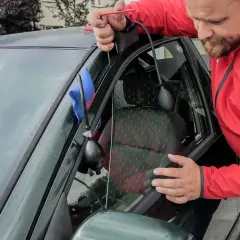 Mężczyzna używa narzędzia do otwierania drzwi, gdy zatrzaśnięte kluczyki w samochodzie jak otworzyć.