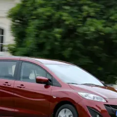 Czerwona Mazda 5 w ruchu, zgrabna i przestronna, idealna na rodzinne wycieczki. Poznaj jej mazda 5 wymiary.
