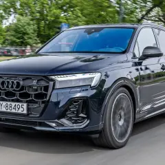 Ciemny Audi Q7 w ruchu, z widocznym grillem i reflektorami. Poznaj audi q7 dane techniczne.