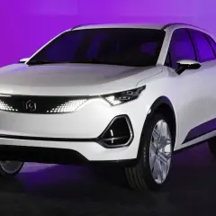 Biały, nowoczesny polski samochód elektryczny z futurystycznymi światłami LED na tle fioletowego światła.