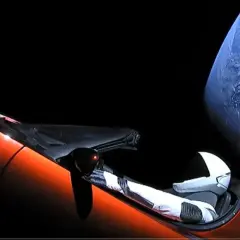 Pomarańczowy Tesla Roadster z manekinem w skafandrze kosmicznym dryfuje w kosmosie obok Ziemi.