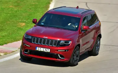 Czerwony Jeep Grand Cherokee na torze. Kierowca ma ciekawe tablice indywidualne pomysły, S1 LNY.