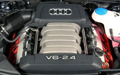 Silnik V6 2.4 z Audi A6 C4. Widoczne logo Audi i elementy układu dolotowego.