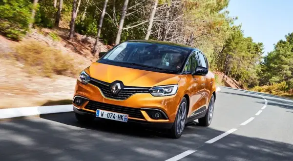 Pomarańczowy Renault Scenic 4 na krętej drodze. Choć wygląda świetnie, warto znać jego potencjalne wady przed zakupem.