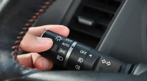 Dłoń reguluje przełącznik świateł: AUTO, światła mijania, światła dzienne.