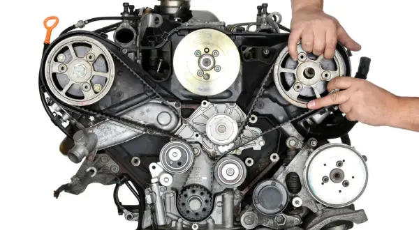 Mechanik sprawdza stan paska rozrządu w silniku samochodu.