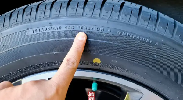 Palec wskazuje na żółtą kropkę na oponie, obok napisu "TRACTION A".