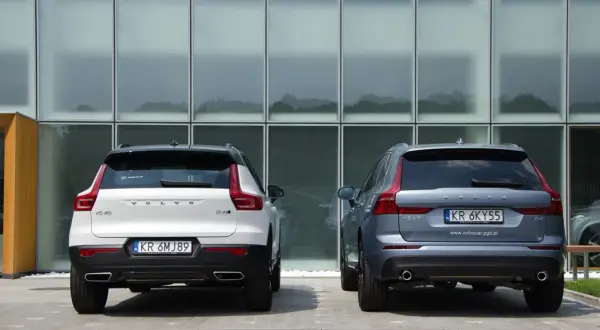 Dwa SUV-y Volvo: białe XC40 i szare XC60, stoją przed nowoczesnym budynkiem. Porównanie ich wymiarów jest łatwe.