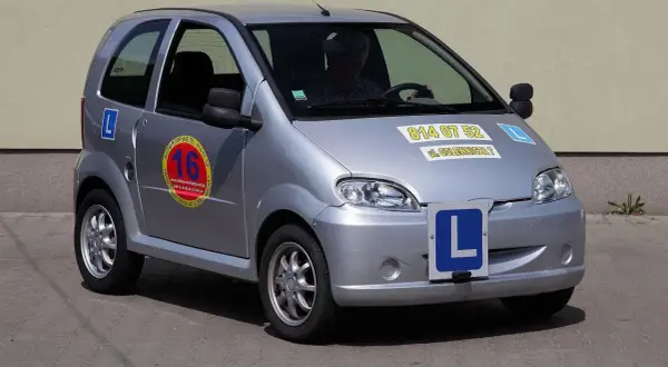Srebrne auto z literką "L" na masce i drzwiach, idealne jako auto dla 15 latka do nauki jazdy.