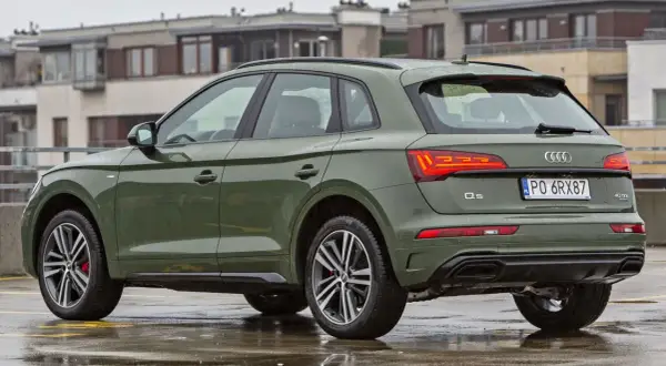 Zielony Audi Q5 na mokrym parkingu. Poznaj jego **audi q5 wymiary** i możliwości.