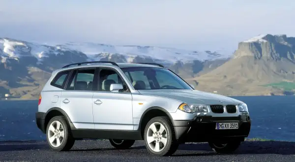 Srebrny BMW X3 E83 na tle gór i morza.