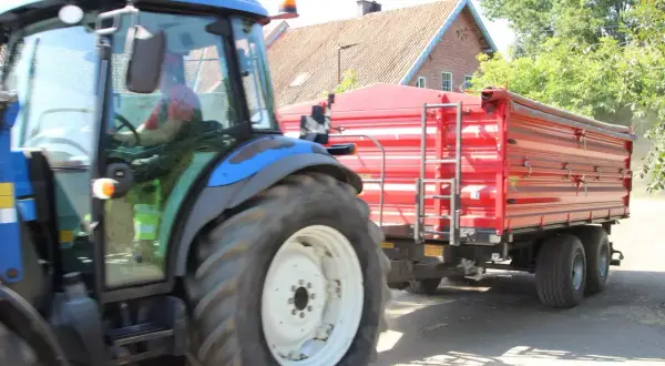 Kierowca w kabinie traktora z przyczepą. Czy na kat B można jeździć ciągnikiem z przyczepą? To pytanie nurtuje wielu rolników.