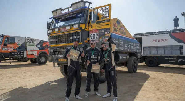 Trzej członkowie zespołu KAMENA Rally Team pozują z pucharami przed ciężarówką DAF.