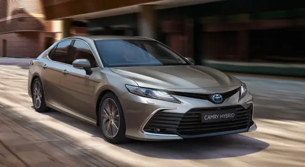 Elegancka, brązowa Toyota Camry Hybrid w ruchu. Poznaj jej imponujące toyota camry wymiary, idealne do miasta i na trasy.