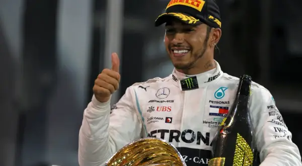 Lewis Hamilton, jeden z najlepsi kierowcy F1 wszechczasów, świętuje zwycięstwo z pucharem i szampanem.