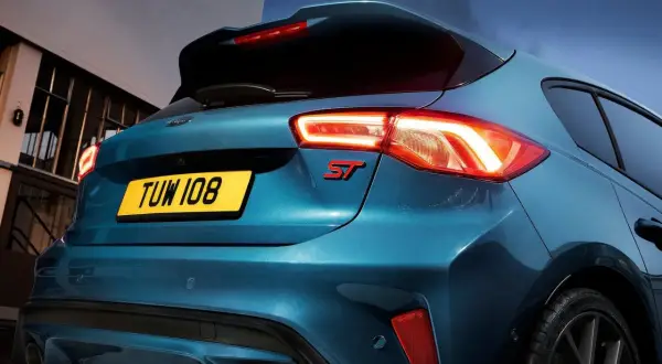 Tylna część sportowego Forda Focus ST 2025 w kolorze niebieskim, z podświetlonymi światłami i czerwonym emblematem ST.