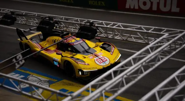 Żółto-czerwony bolid Ferrari z numerem 83 na torze podczas wyścigu Le Mans 24h.