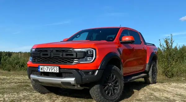 Pomarańczowy Ford Raptor na tle nieba i lasu. Zastanawiasz się nad jego **spalaniem**?