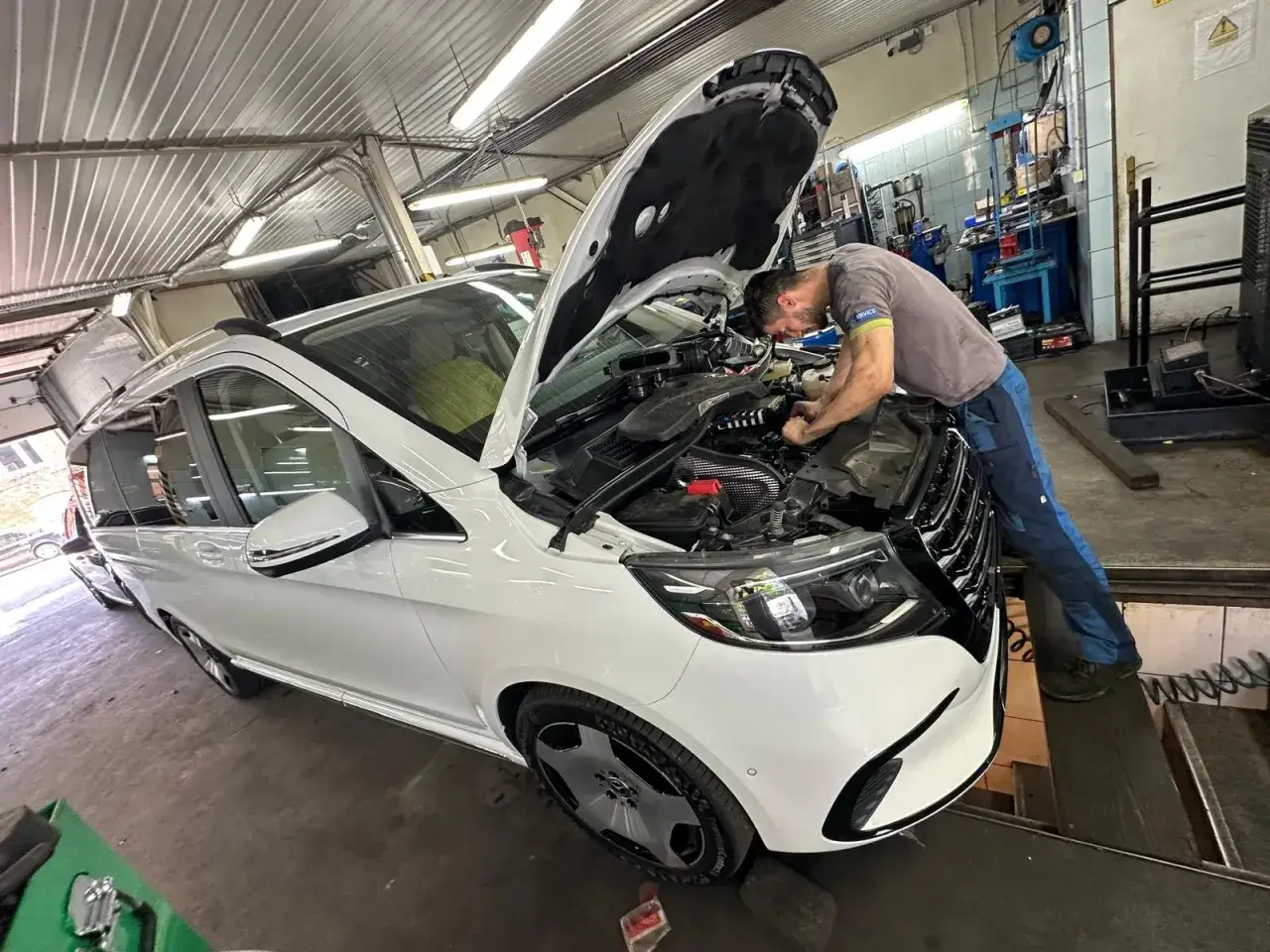 Mechanik naprawia białe auto, które straciło moc. Podejrzewamy, że problem leży w silniku benzynowym.