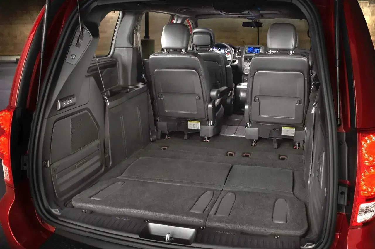 Wnętrze Dodge Grand Caravan z rozłożonymi siedzeniami i dużą przestrzenią bagażową. Idealny na rodzinne wycieczki.