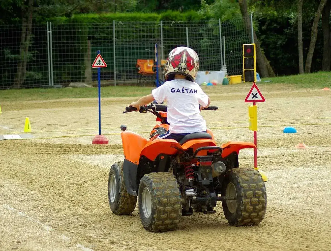 Chłopiec w kasku na quadzie uczy się jeździć na specjalnym torze. To jego pierwsza kategoria na motor.