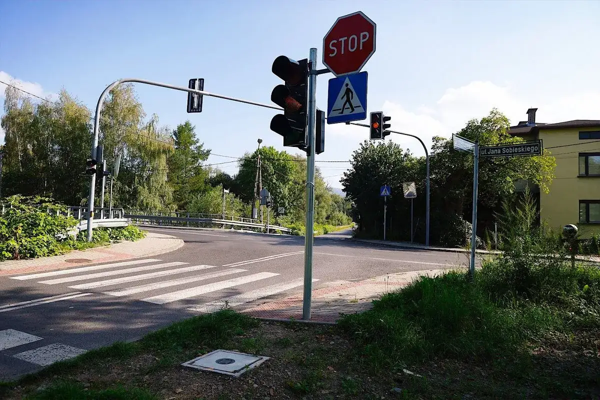 Przejazd na żółtym świetle. Na skrzyżowaniu z pasami dla pieszych i znakiem STOP, sygnalizacja świetlna pokazuje pomarańczowe światło.