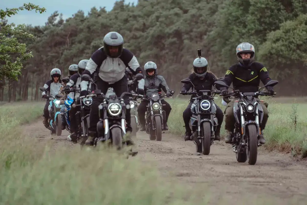 Grupa motocyklistów na najmocniejszym motocyklu 125 przemierza leśną drogę.