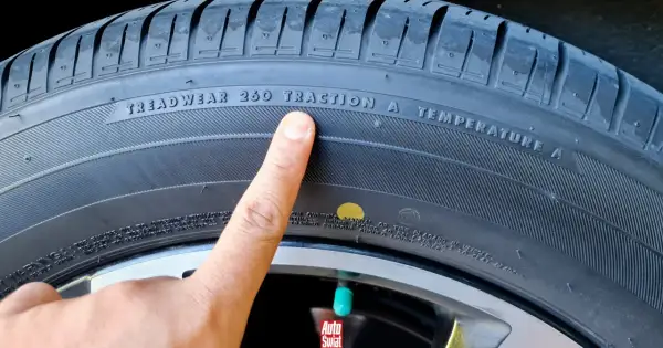 Palec wskazuje na żółtą kropkę na oponie, obok napisu "TRACTION A".