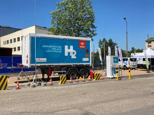Naczepa z napisem "Zeroemisyjne paliwo wodorowe" i dystrybutor H₂. Wodór jako paliwo przyszłości.