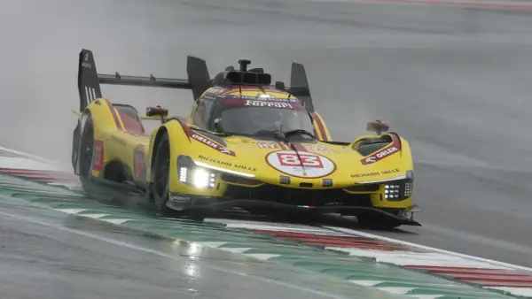 Żółty bolid Ferrari z numerem 83 na torze podczas deszczowego wyścigu 24h Le Mans.