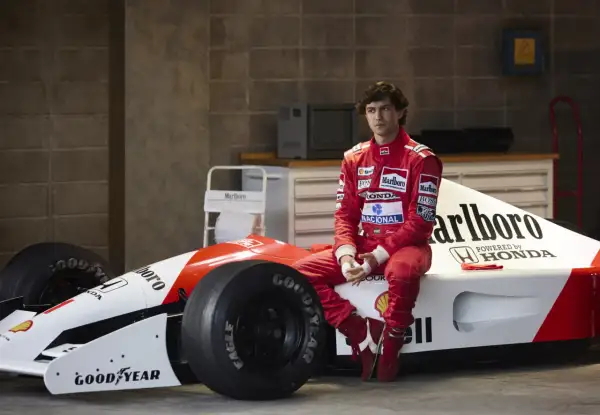 Młody kierowca w czerwonym kombinezonie siedzi na bolidzie F1. Czy to przyszły były brazylijski kierowca formuły 1?